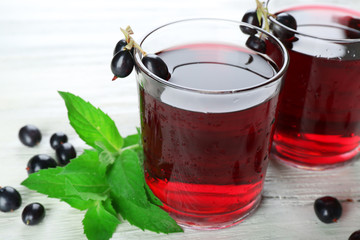 Glasses of fresh blackcurrant juice wooden table background