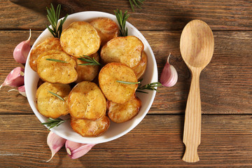 Delicious baked potato with rosemary in bowl on table close up