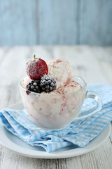 Delicious ice cream with fresh frozen berries, on color wooden background