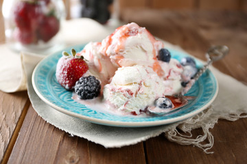 Delicious ice cream with fresh frozen berries and sauce, on wooden background