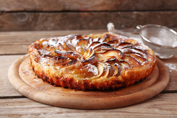 Homemade apple pie on cutting board on wooden background