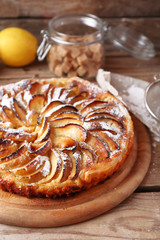 Homemade apple pie on cutting board and fresh apples on wooden background