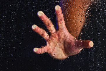 Obraz na płótnie Canvas Male hand behind wet glass, close-up