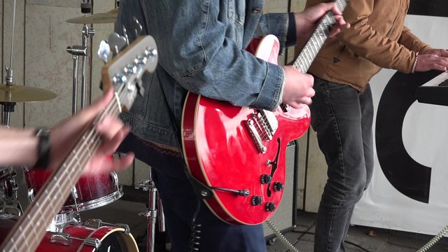 Young musicians rock band play guitar synthesizer and drum sing in outdoor concert. Static shot. Street music day. 4K
