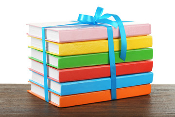 Stack of books with ribbon on light background