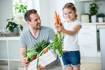 Vater und Tochter mit Gemüsekiste in der Küche