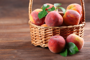 Fresh peaches in wicker basket on wooden background