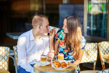 Young romantic couple in a cozy outdoor cafe in Paris, France