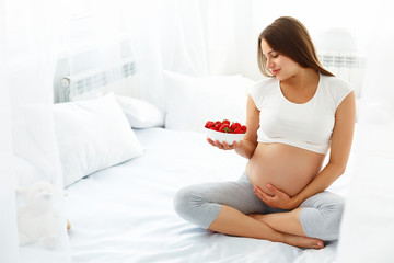 Obraz na płótnie Canvas Pregnant Woman Eating Strawberry at home. Healthy Food Concept.