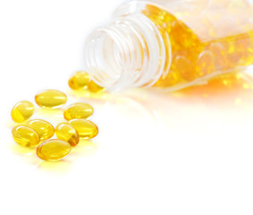 Pile of omega 3 fish oil capsules spilling out of a bottle over