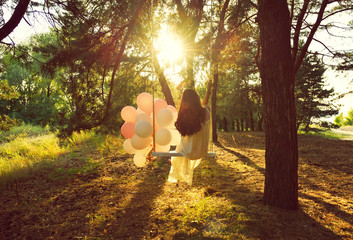 Young woman is swinging on a swing in summer pine forest. Image