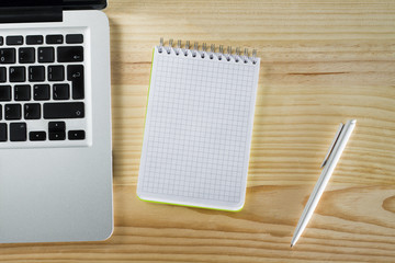 Laptop blank notepad and pen on wooden desktop