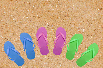 Fototapeta na wymiar colorful beach shoes on yellow sand background