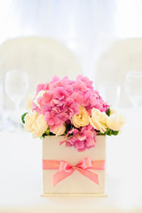 Flower composition for an event party or wedding reception is on the white table