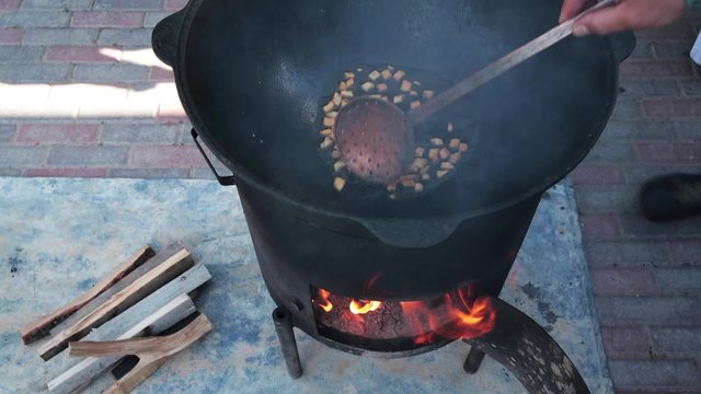 Uzbek national dish pilaf in a large cast-iron cauldron on the fire, the cooking process, fried pieces of fat tail, basis ​​constituting food rice, lamb, carrot, mutton fat, sesame oil, onion, garlic