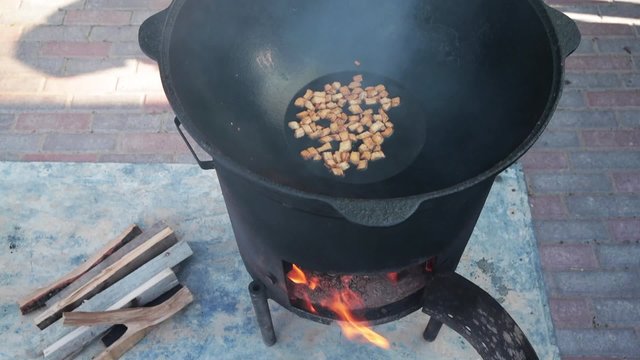 Uzbek national dish pilaf in a large cast-iron cauldron on the fire, the cooking process, fried pieces of fat tail, basis ​​constituting food rice, lamb, carrot, mutton fat, sesame oil, onion, garlic