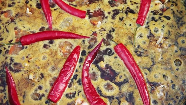 Uzbek national dish pilaf in a large cast-iron cauldron on the fire, sliced red carrots, cold water, add whole of garlic and red chili pepper, boiling, rice, lamb, mutton fat, the fat tail, sesame oil