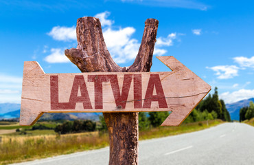 Latvia wooden sign with road background