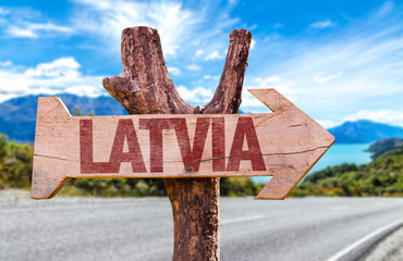 Latvia wooden sign with road background