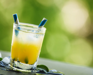 Screwdriver cocktail with ice on a blurred green background, sel