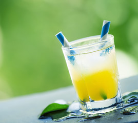 Screwdriver cocktail with ice on a blurred green background, sel