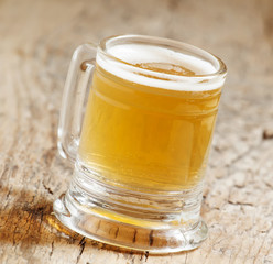 light beer in a little old-fashioned mug on old wooden table, se