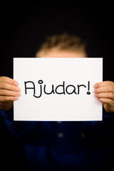 Child holding sign with Portuguese word Ajudar - Help