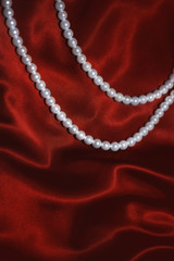 white pearl necklace on a red silk