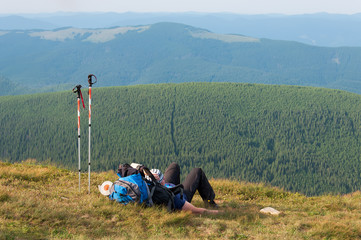 Tired hiker relaxes on a slope in the mountains