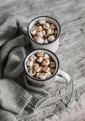 hot chocolate with marshmallows in ceramic mugs on a light wooden surface