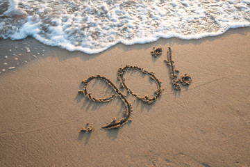Novanta percento scritto sulla sabbia in riva al mare