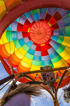 Colorful hot air balloon photographed from basket during fly.