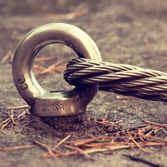 Detail of steel bolt anchor eye in rock. The end knot  of steel rope. Climbers path in rocks via...
