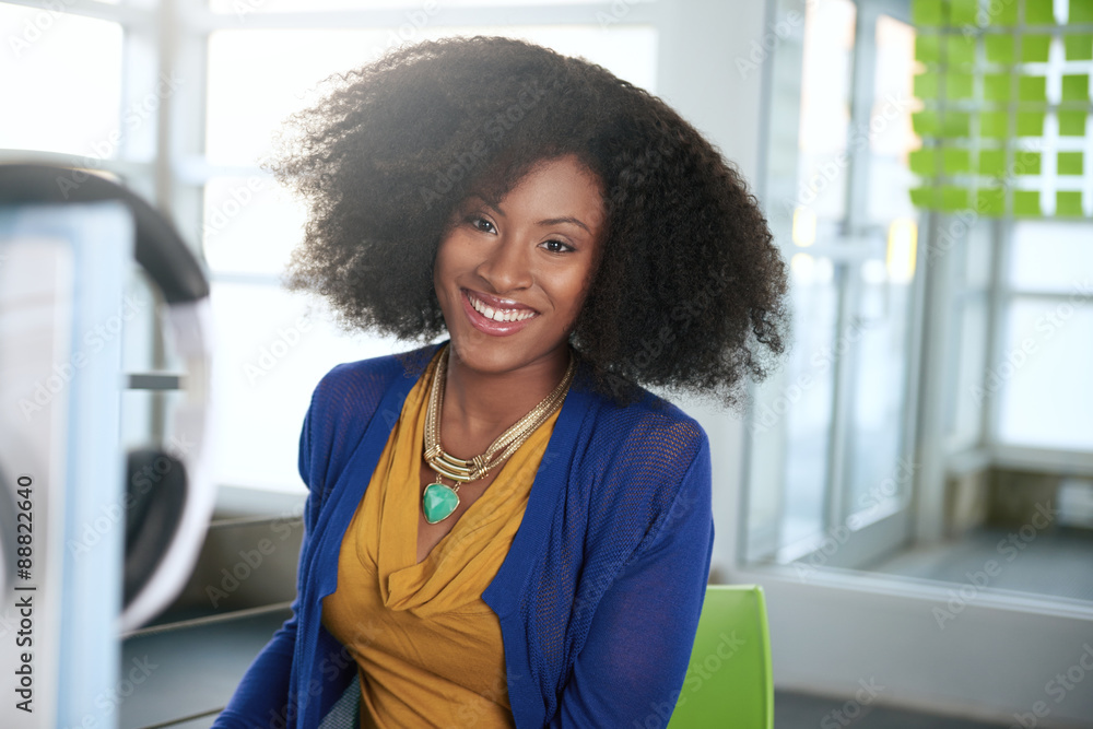 Wall mural portrait of a smiling woman with an afro at the computer in