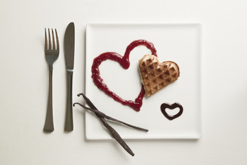Heart waffles, marmalade, chocolate sauce, vanilla sticks on a white background