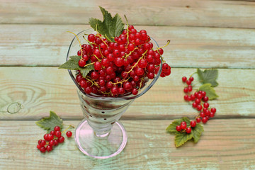 Fototapeta na wymiar Red berries in glass on wooden background