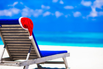 Sun chair lounge with red Santa Hat on tropical white beach and