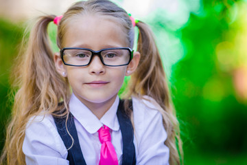 Fototapeta na wymiar Portrait of happy little school girl in glasses outdoor