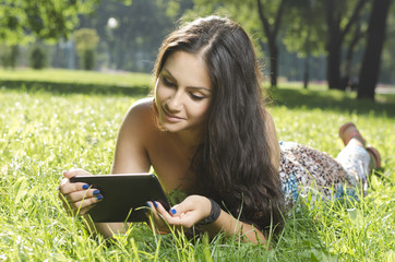 beautiful girl lying on the grass with the tablet