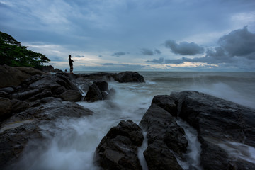 Silhouette of a fisherman, man fishing on a sea from the rock at
