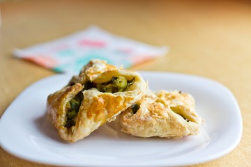 Fresh baked homemade puff pastry cakes with onion and egg on white dish. Focus on cakes. Blurred background