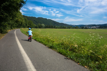 boy with helmet riding bicycle alone on the way outside the city