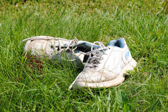 Old dirty sport shoes on grass