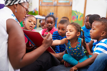 Teacher reading a book with a class of preschool children - Powered by Adobe