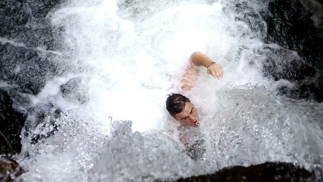 High angle of fit man swimming under waterfall 