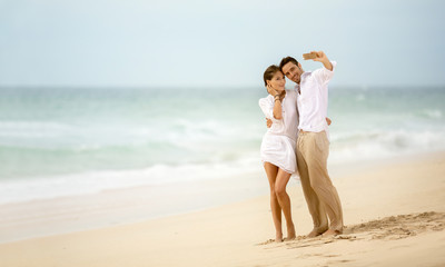 Beach vacation couple taking selfie photograph using smartphone