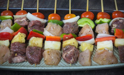 Skewed barbecue of diced chicken meat and beef meat with pineapple, onions, green and red bell peppers, cherry tomatoes. Marinated in herbs.