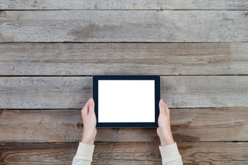 female hands holding digital tablet computer with isolated screen over old grey wooden background table.
