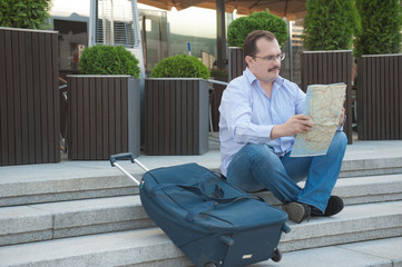Obraz premium Trendy adult man in the town with touristic map outdoors.
