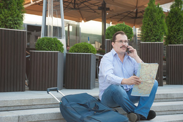 Trendy adult man in the town with touristic map outdoors.